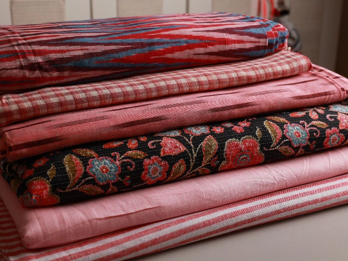 Stack of different red, pink fabrics sourced by ATELIER A.PUUR.A 